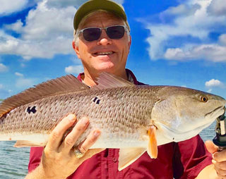 catching-fish-03 Man holding a large fish after going on a Whiskey Bayou charter
