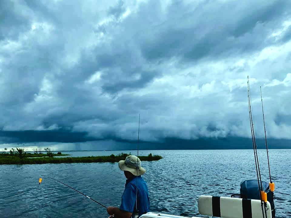 Overcast marsh dramatic Angler fishing on the water while great gray clouds loom overhead