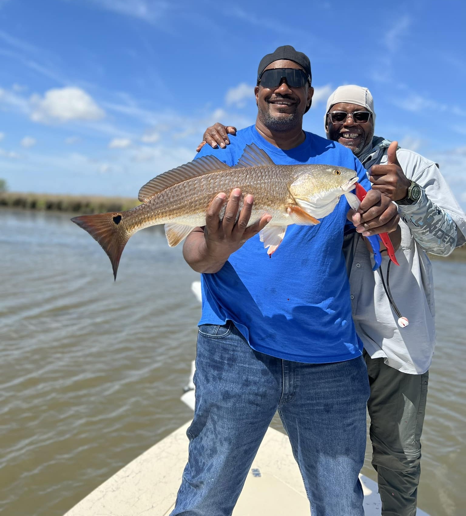supportive anglers 2 Once man proudly holding up his catch for the camera while his buddy stands behind him with one hand on his shoulder and the other giving a thumbs up