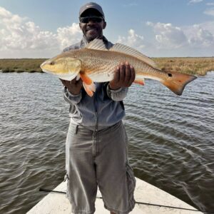 Man in gray holding up his catch