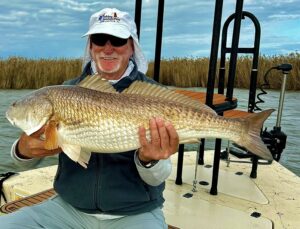 An angler sitting while holding up his catch for the camera.