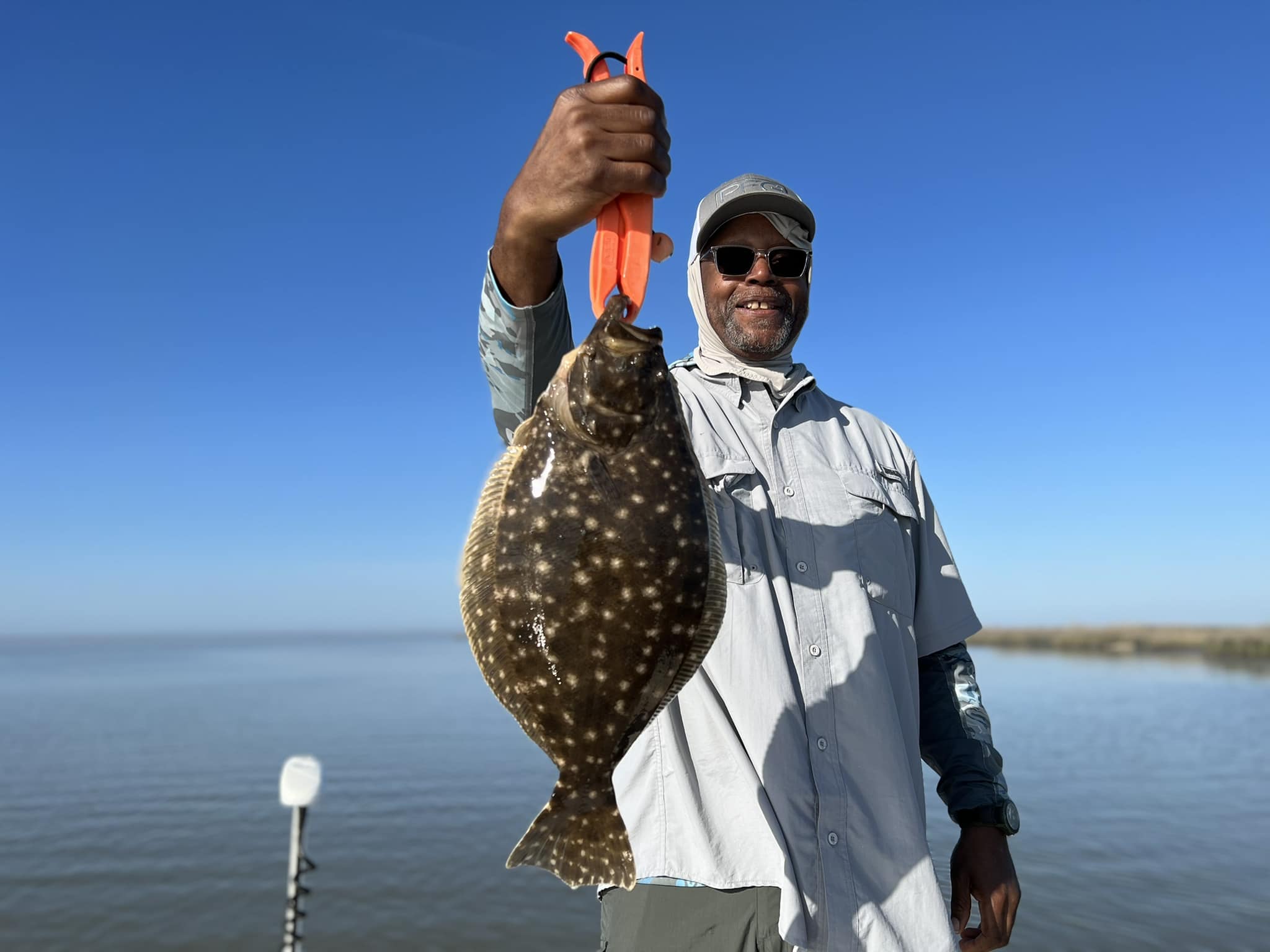 Happy guy in grey hood proudly holding up his catch for the camera